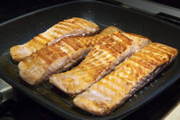 Steak of a fish Salmon cooking in a hot pan on a kitchen stove. 