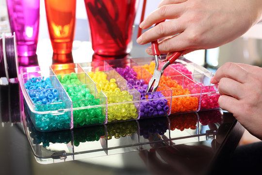 Kolorowe koraliki.Kobieta tworzy kolorową biżuterię z plastikowych koralik&oacute;w