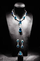 Set of luxury jewelry made of white gold with diamonds and sappfires on a stand.