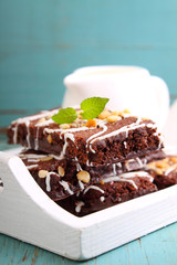 chocolate brownie cake with nuts and ising on a white tray