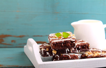 chocolate brownie cake with nuts and ising on a white tray