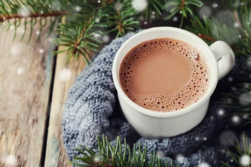  Kop warme chocolademelk of warme chocolademelk op gebreide achtergrond met dennenboom en sneeuweffect, traditionele drank voor de winter © juliasudnitskaya
