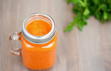 Healthy carrot smoothie in a jar on wooden background