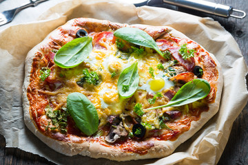 Homemade salami pizza with spinach and quail eggs