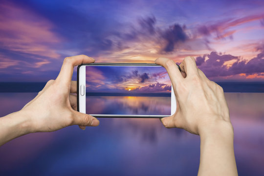 Girl taking pictures on mobile smart phone in sunset beach,Phuke