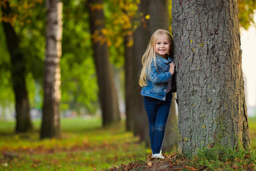 Little girl hugging a tree and smile in park