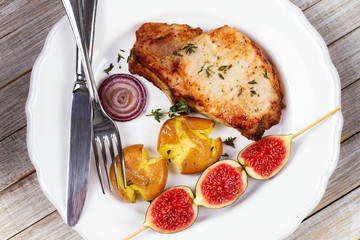 Grilled Pork Chop with Figs on Scewer, Crisp Roasted Potatoes and Thyme. View from above, top studio shot
