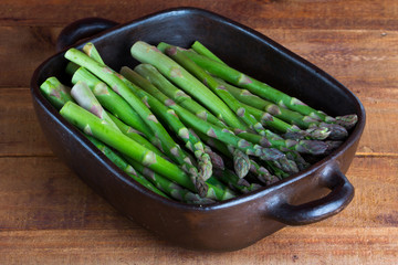 Green asparagus in clay bowl on table
