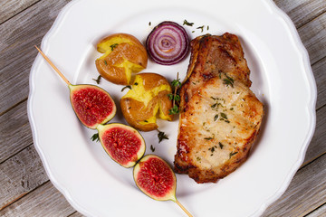 Grilled Pork Chop with Figs on Scewer, Crisp Roasted Potatoes and Thyme. View from above, top studio shot