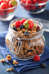 homemade healthy granola in glass jar and berries