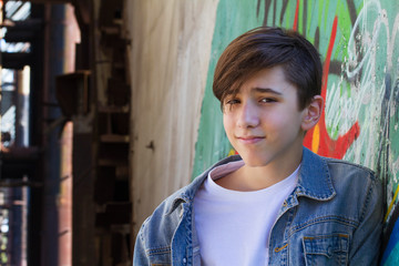 Smiling teen boy next to graffiti painted wall