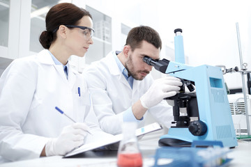 Naklejka na ściany i meble scientists with clipboard and microscope in lab