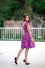 Beautiful brunette young woman wearing dress and walking on the street