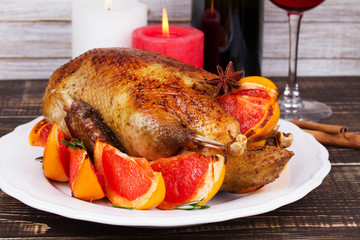 Festive Christmas duck baked with grapefruits and rosemary, glass of wine and candles