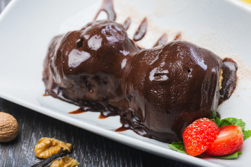 lush and beautiful chocolate truffle dessert with strawberries on a white plate on a wooden table in a restaurant