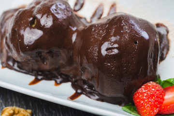 lush and beautiful chocolate truffle dessert with strawberries on a white plate on a wooden table in a restaurant
