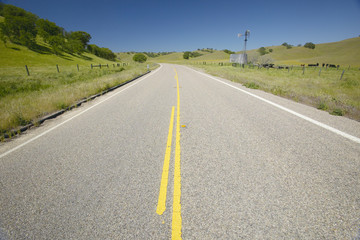 A yellow line down the center of old route 58, CA near an old windmill and farm