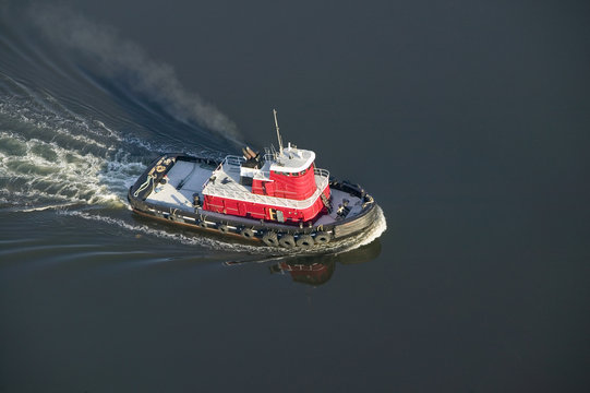 A aerial view of a bright red tug boat outside of Portland Maine