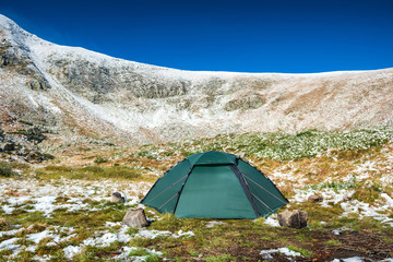 Green tent in snow mountains