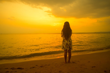 Fototapeta na wymiar Woman standing on the beach looking at sunset