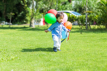 Fototapeta premium Little boy holding balloon and playing at park