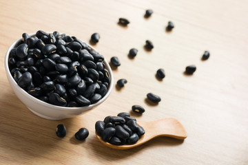 Fototapeta na wymiar Black bean in white melamine cup and wooden spoon on wooden tabl