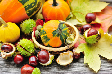 Naklejka na ściany i meble Fresh chestnuts with autumn leaves and mini pumpkins on wooden b