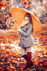 Beautiful young woman is in an autumn park with an umbrella