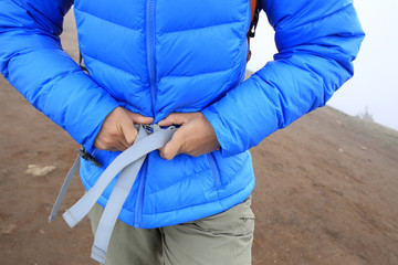 woman hiker buckle up the belt of backpack on mountain peak