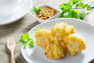 Crispy fried corn ball in a white plate on wooden table,Vegetari