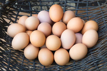Eggs chicken in a basket of dried vine on wooden background.