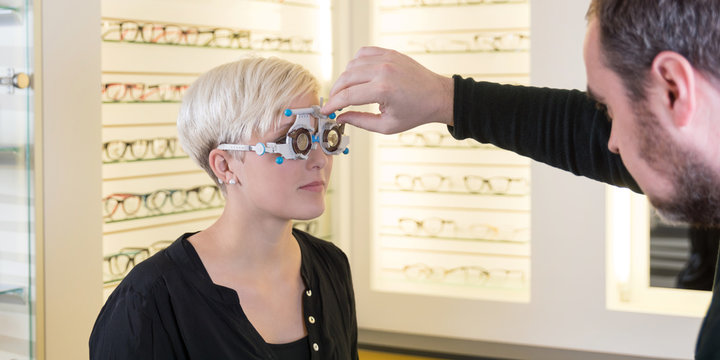 Optiker beim einstellen einer Testbrille bei einer Kundin