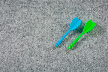 Darts, green and blue placed on the gray carpet.