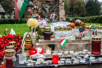 White candles, flowers of various colors and bows with the flag of Hungary in the grave of one of the victims of the Hungarian revolution of October 1956, in Budapest