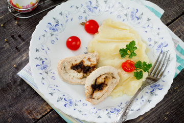 Chicken roll with prunes and nuts on a wooden table