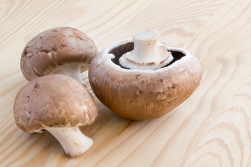 Three chestnut mushrooms on a wooden cutting board