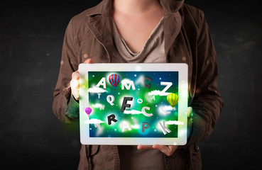 Fototapeta na wymiar Young person showing tablet with abstract letters and sky