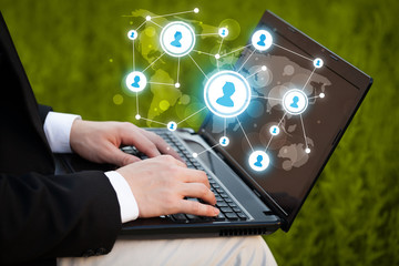 Close up of hand with laptop and social media icons