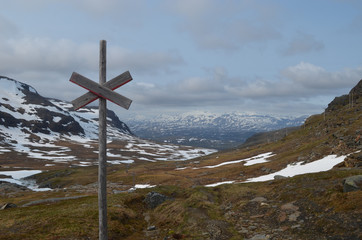 Wooden cross on pole marking trail in Swedish subarctic mountains