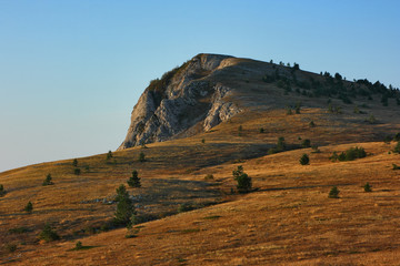 Highlands of Crimean mountains. View on a plateau with a typical for such terrains karst formations and steep precipices in morning sun.