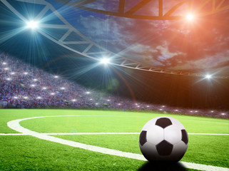 Soccer ball on green stadium, arena in night illuminated