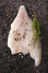 sea bream fillet with spice mix on a dark marble surface