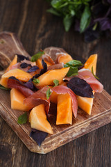 Appetizer, melon with jamon and Basil, on a wooden dosochka.selective focus