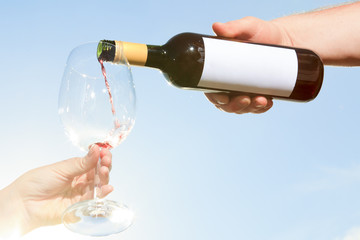 couple drinking a bottle of red wine outside