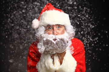 Photo of Santa Claus in eyeglasses blowing snow 