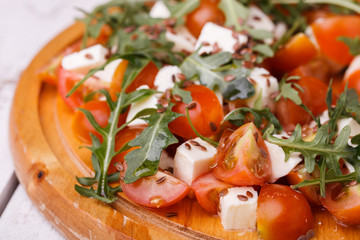 Salad of tomato, mozzarella and arugula with flax seed.