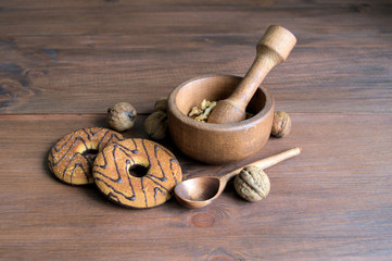 Walnuts. On the wooden cover wooden mortar with pestle. In a mortar kernels to grind. Near a small...