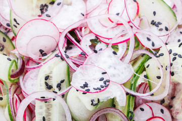 Salad with cucumber, radishes, red onion and black sesame seeds.