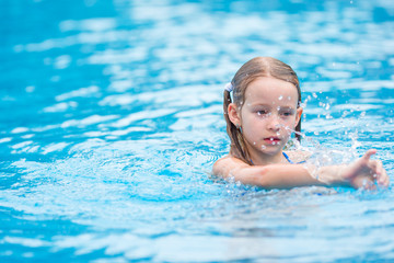 Fototapeta na wymiar Adorable little girl having fun in outdoor swimming pool
