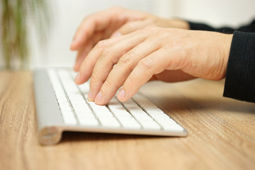 Closeup of male hands typing on computer keyboard